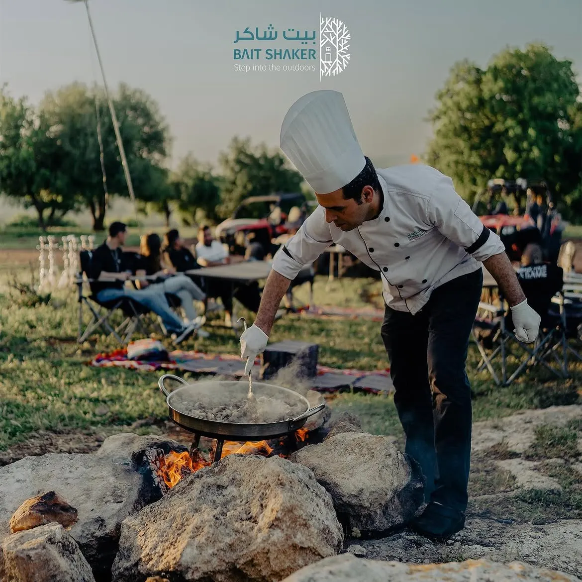 A chef cooking over an open fire at a Bait Shaker camp