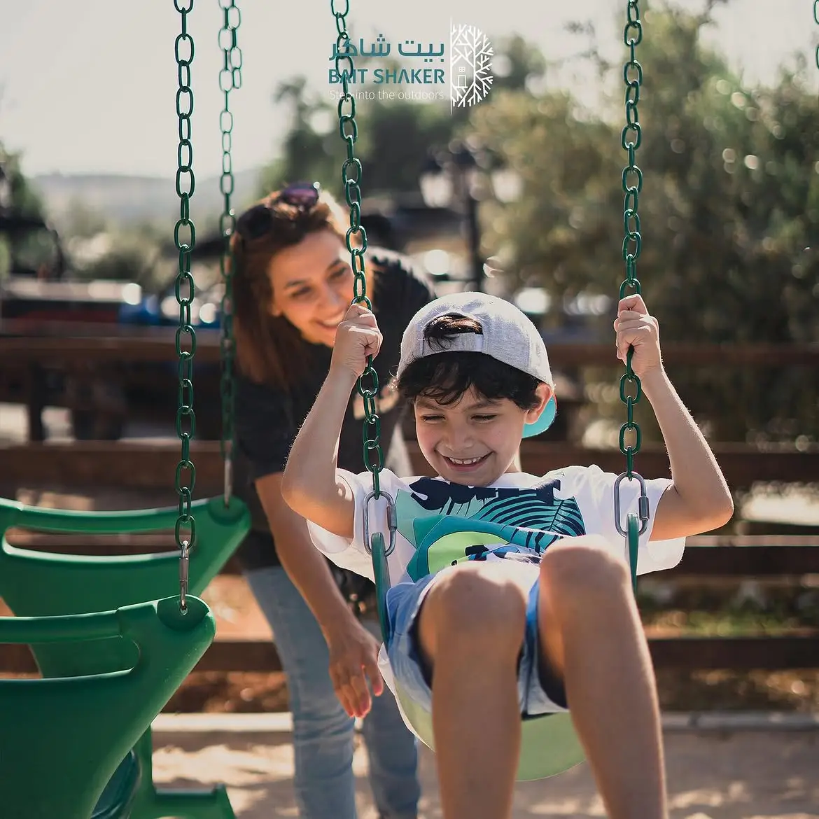A parent and child on the swings at Bait Shaker's shaded kids' play area